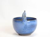 a small blue bowl with a bird perched on it