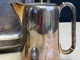 a silver tea pot sitting on a table next to a silver kettle