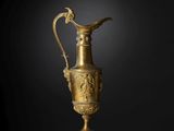 un vase en or richement décoré, surmonté d'un oiseau