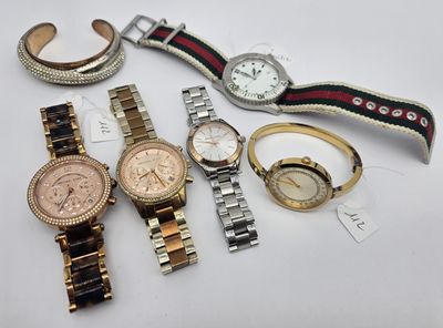 several watches and bracelets are sitting on a white surface