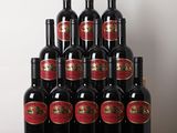 Des bouteilles de vin rouge sont posées sur une table devant un mur blanc.