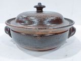 a brown and black pot with a lid on a table
