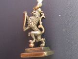 a gold necklace with a lion on it on a black surface