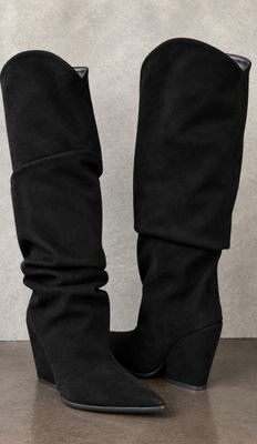 a pair of black boots sitting on top of a wooden floor