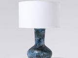 La lampe de table est bleue et est équipée d'un abat-jour blanc.