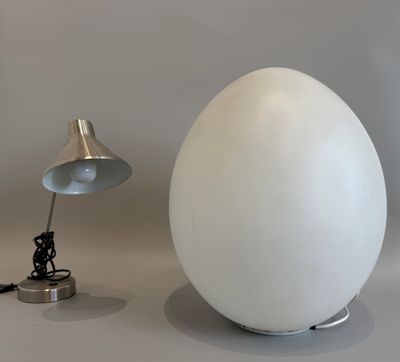 a white egg sitting next to a lamp on a table