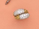 une paire de ciseaux et une bague posés sur une surface rose