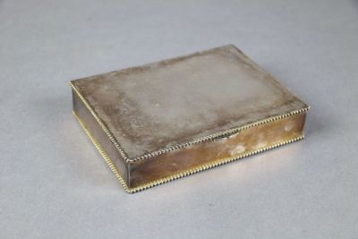 une vieille boîte en argent comportant un petit carré à l'intérieur, sur un fond blanc