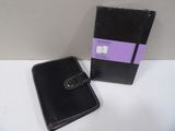 a black notebook with a black cover next to a purple box