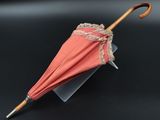a pink umbrella with lace on it on a black surface