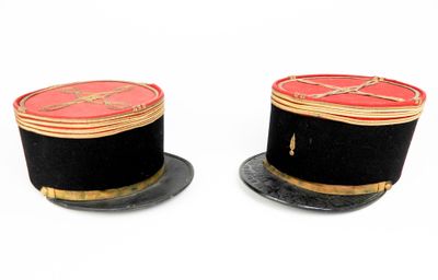 une paire de chapeaux noirs et rouges avec des bordures dorées sur fond blanc