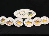 cinq assiettes ornées de poissons peints, posées sur une table noire