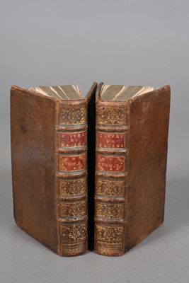 two old books sitting on top of each other on top of a table