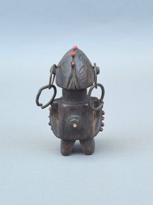 une petite statue représentant un robot avec une perle rouge sur la tête