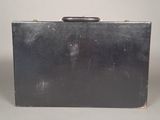 a black suitcase with a brown handle on a gray surface