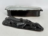 une figurine de chat noir posée à côté d'un plateau en métal