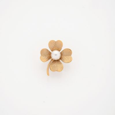 a gold flower brooch with a pearl in the center