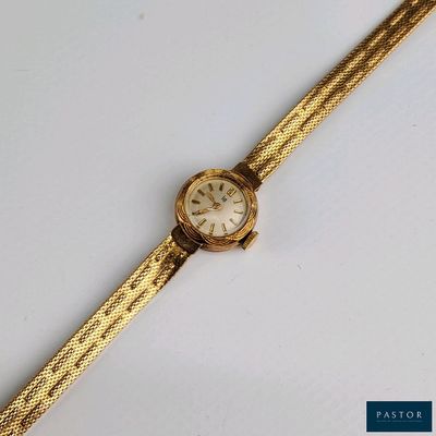 une image représentant une montre en or avec un cadran blanc posée sur une surface blanche