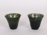 une paire de vases noirs et verts posés sur une surface blanche