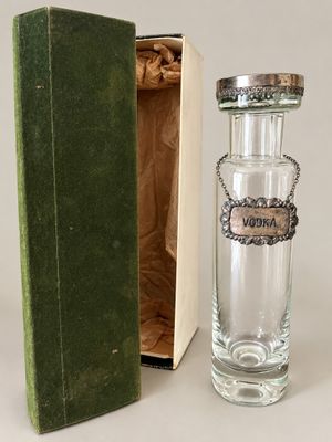 a small glass bottle with a silver lid in a green box