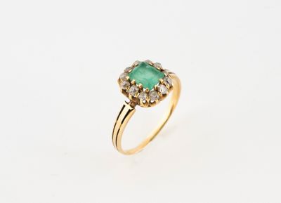 a gold ring with an emerald stone surrounded by diamonds