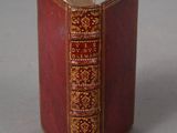 a red book with gold trim sitting on a table