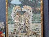a picture of two cheetah sitting on a shelf next to a painting