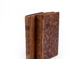 an old book with a leather cover sitting on top of a white surface