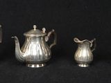 four pieces of silver tea and coffee set on a black background