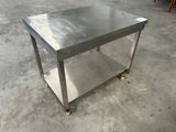 une photo d'une table en acier inoxydable montée sur roulettes dans un entrepôt