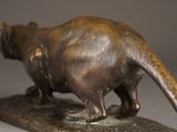 bronze statue of a cat on a rock on a gray background