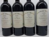 quatre bouteilles de vin sont alignées sur une surface blanche