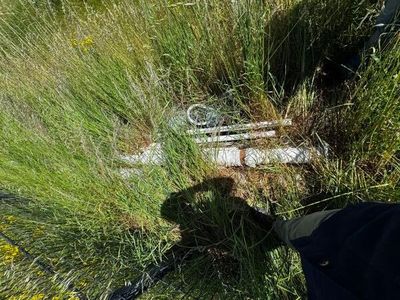 un sac noir posé dans l'herbe près d'une clôture