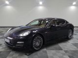 La Porsche Panamera noire est garée sur un sol en carrelage à damier.