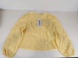 Le pull est jaune et porte une étiquette blanche.