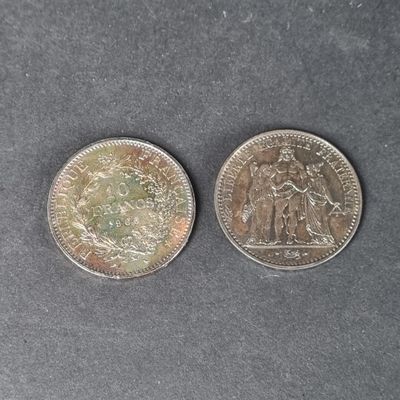 two silver coins sitting side by side on a gray surface