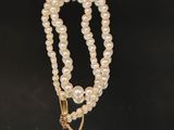 un collier de perles blanches avec un fermoir en or