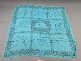 a blue scarf with black writing on it sitting on top of a table