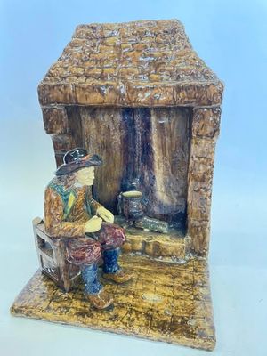 une figurine représentant un homme assis sur un banc devant une cabane