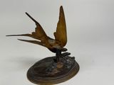 a bronze statue of a bird sitting on a base
