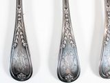 three spoons and a fork are sitting side by side on a white surface