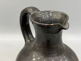 a black vase that is sitting on a white surface