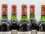 six bottles of red wine lined up in a row on a table