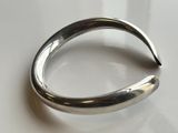 silver plated bracelet with curved design on a white surface