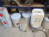 many cans of paint sitting on the floor next to a shelf