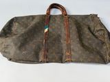 un vieux sac Louis Vuitton avec une poignée marron et des anses marron