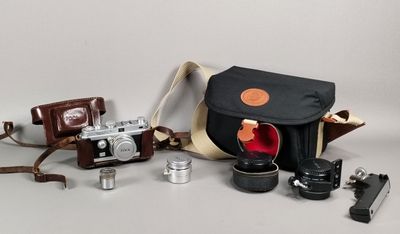 a camera, a camera case, a lens, and other items on a table