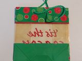 a green and red gift bag with a tag attached to it