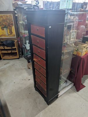 a tall black and red chest of drawers in a store