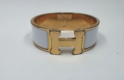 un gros plan d'un bracelet doré et blanc posé sur une surface blanche
